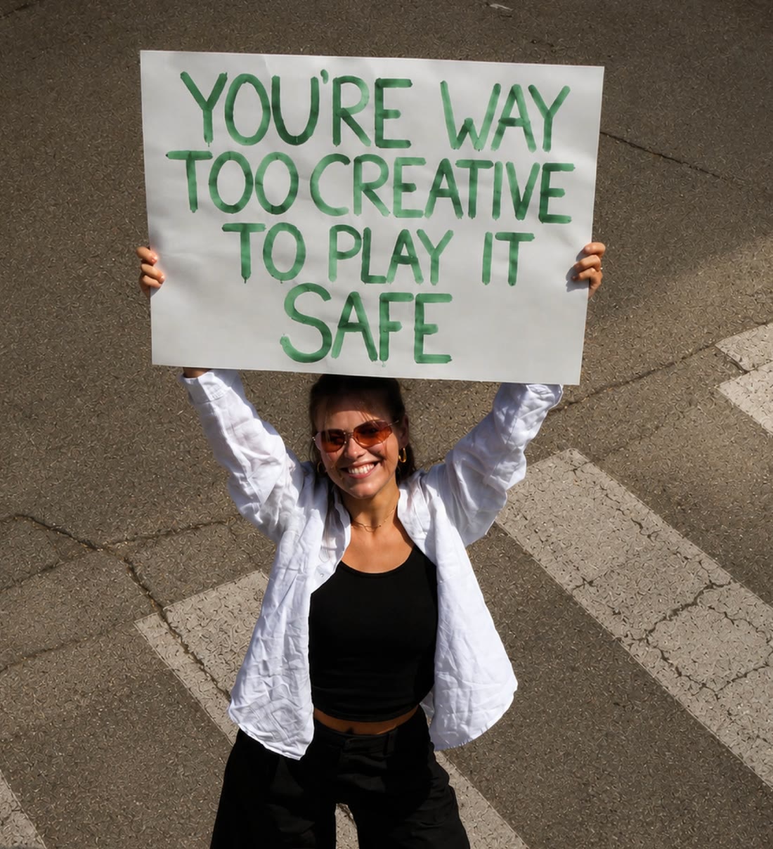 Charisia houdt een bord omhoog met de tekst: you're way too creative to play it safe